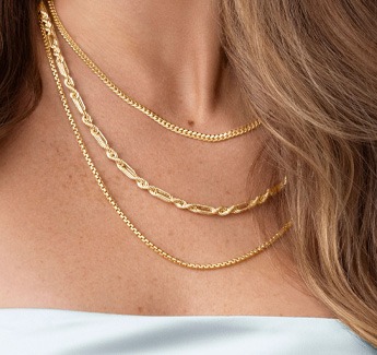 Closeup image of a woman wearing layered necklaces.