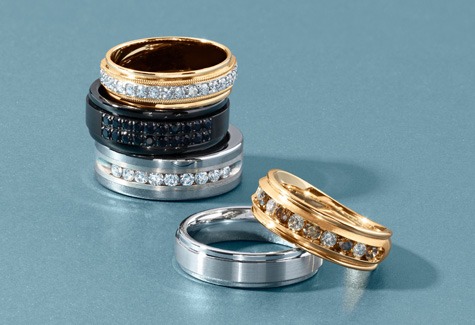 Men's Engagement Ring Styles Stack of men's engagement and wedding bands in gold, silver, and black metal | REEDS Jewelers