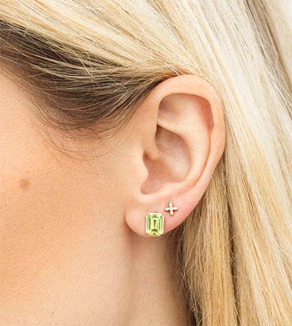 Gold and gemstone stud earrings layered on ear