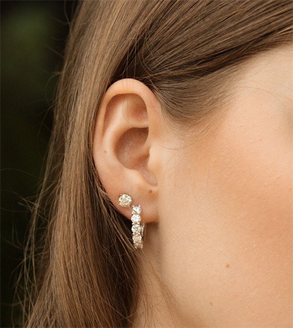 Mixed hoop and stud earrings layered on ear
