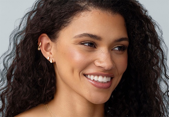 Woman wearing multiple diamond stud earrings in stacked ear piercings