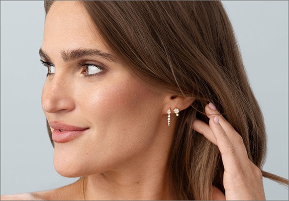 Woman wearing layered gold hoop and huggie earrings