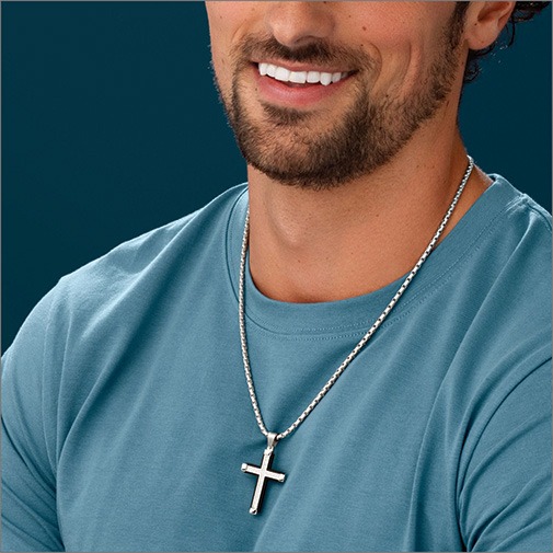 Close up of man wearing a white gold chain with a white gold cross pendant