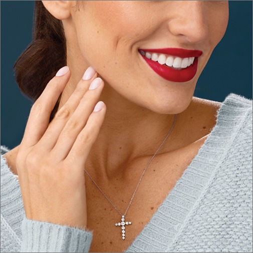 Close up of woman wearing a white gold chain with diamond cross pendant