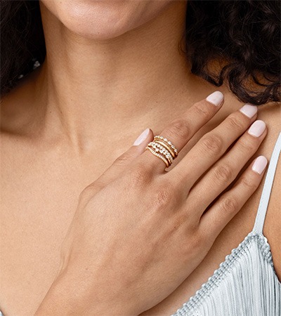 Ring Stacking Ideas for One Finger Model wearing multiple delicate gold rings stacked together on one finger