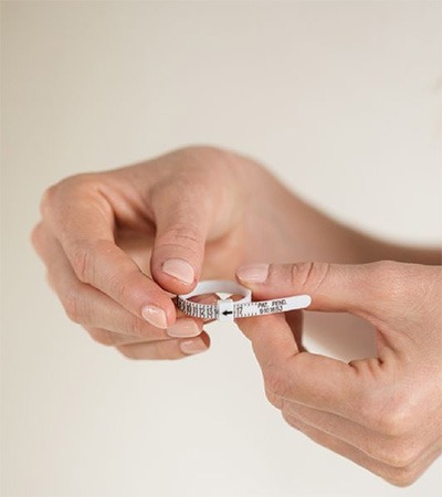 Adjusting a Ring Sizer for an Accurate Fit Hands threading a ring sizer through its slot to create an adjustable loop around the finger
