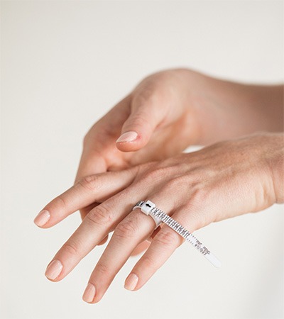 Checking Ring Sizer Fit and Ring Size Hands checking the fit of a ring sizer around a finger to determine the correct ring size