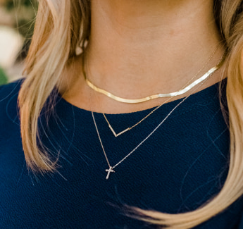 Closeup image of a woman wearing layered necklaces.