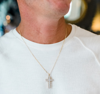 Closeup image of a man wearing a cross pendant necklace.