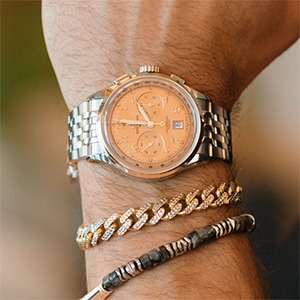 Orange dial chronograph watch with layered bracelets for warm complexions