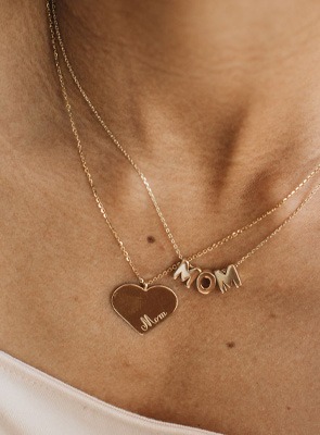 Woman wearing gold heart pendant and &ldquo;Mama&rdquo; name necklace &ndash; personalized Mother&rsquo;s Day jewelry